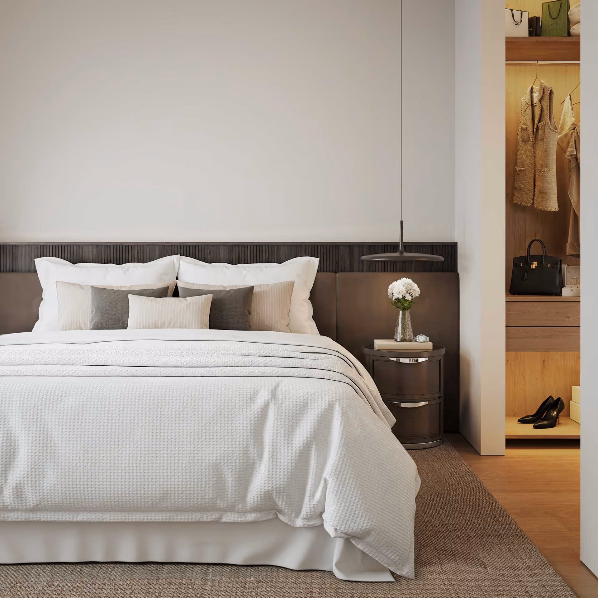 Quarto moderno com cama grande, almofadas em tons neutros, mesa de cabeceira com vaso de flores e armário aberto com roupas e acessórios.