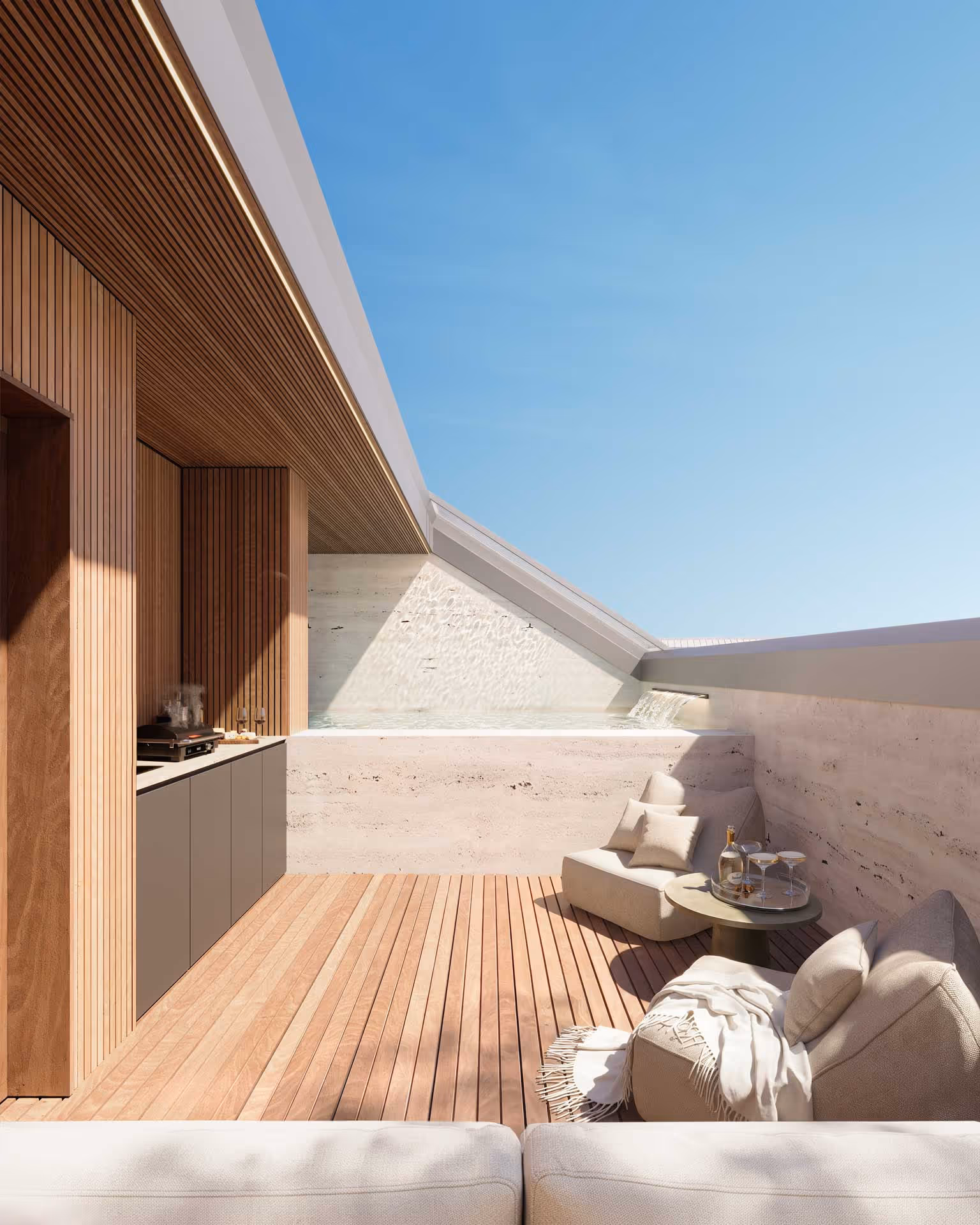 Terraço de luxo com mobiliário confortável, churrasqueira, e piscina com cascata sob um céu azul claro.