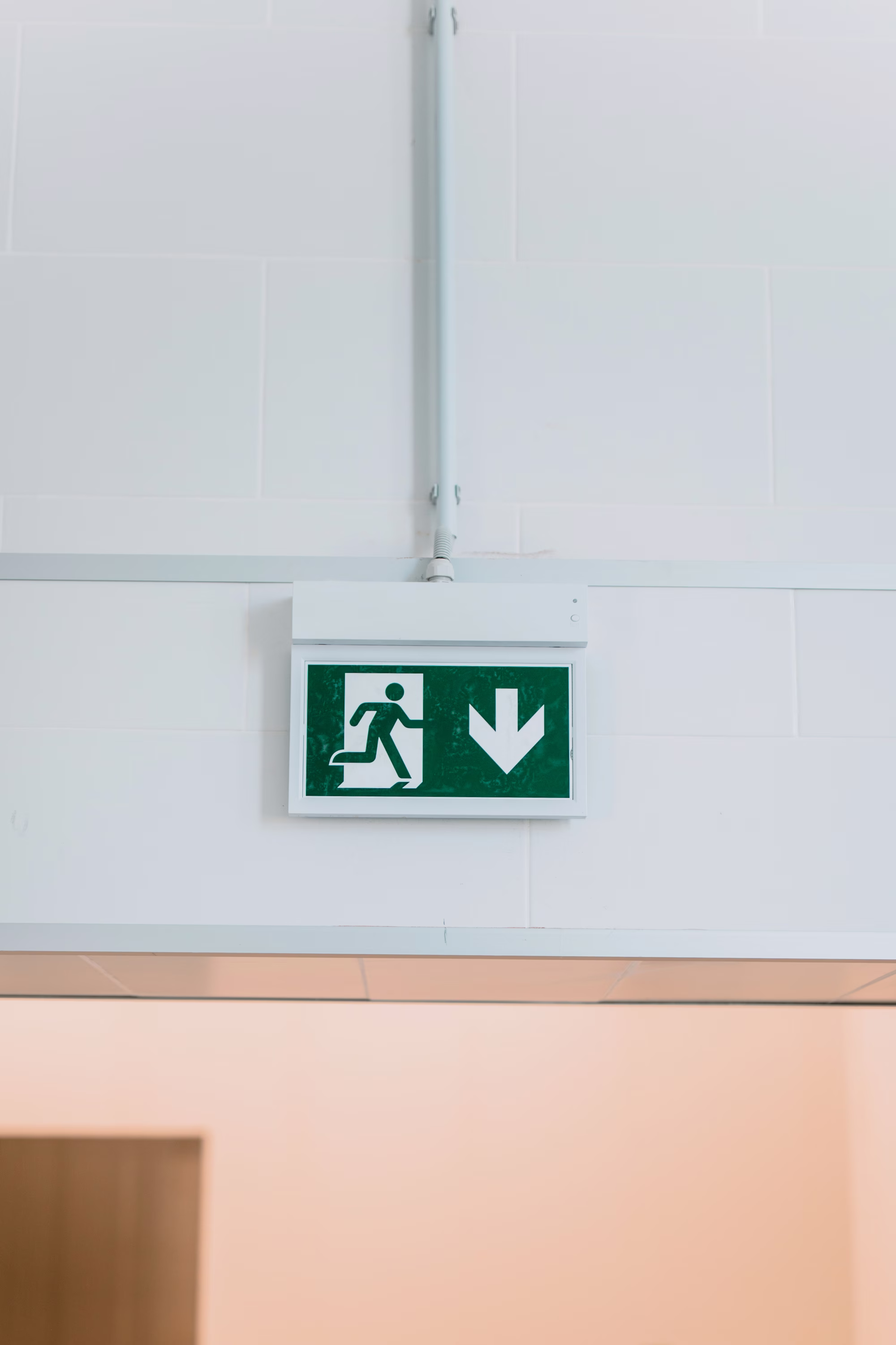 Green emergency exit sign on a tiled wall
