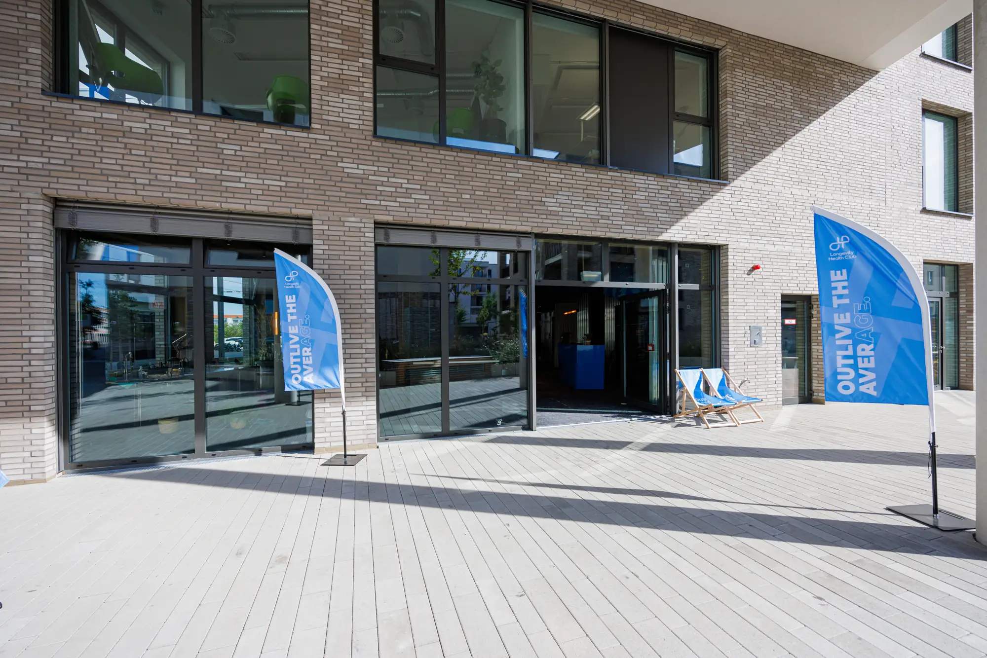Eingang der Longevity Health Lounge mit blauen Fahnen unter der Arkade