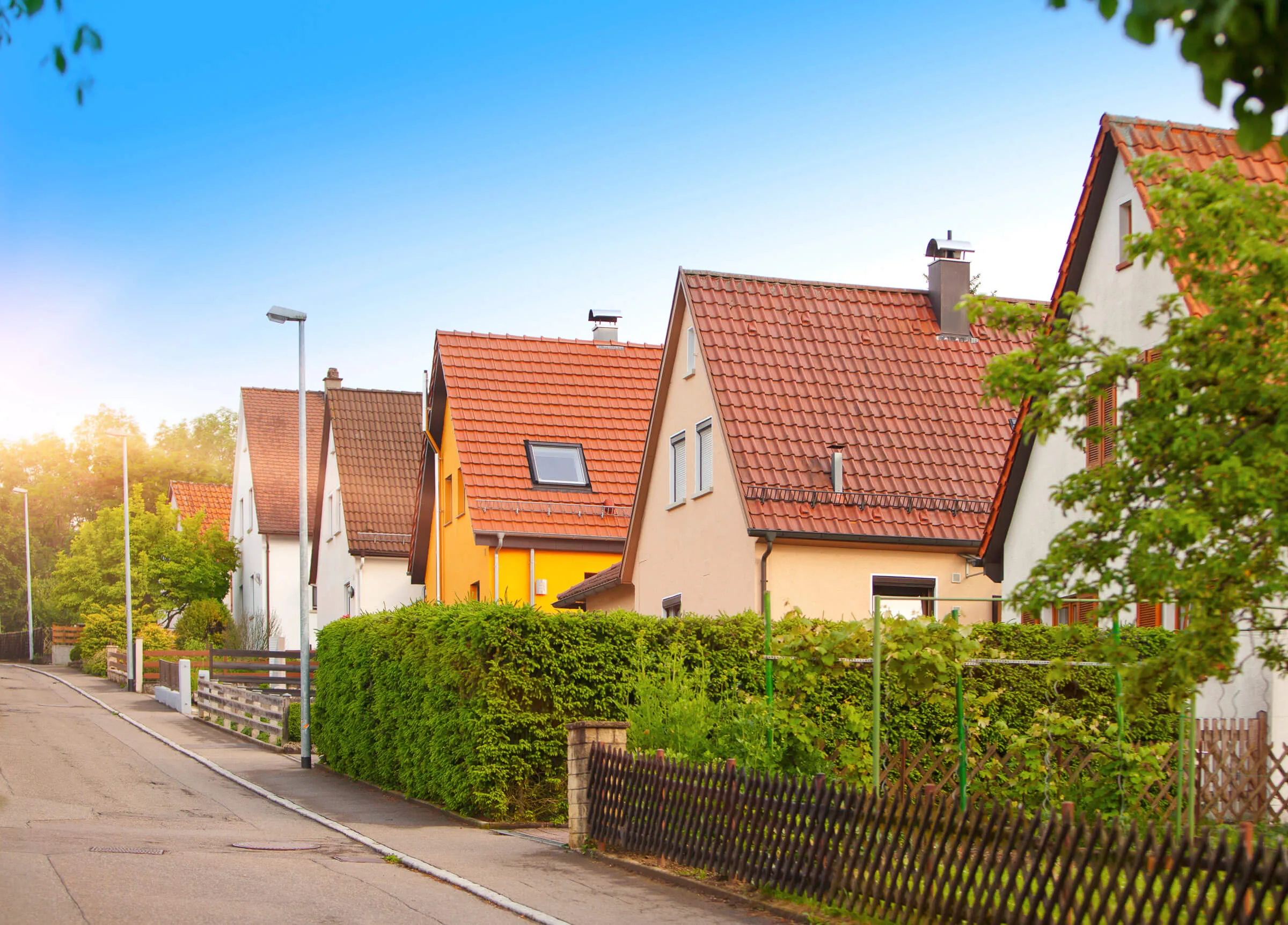 KI-generiertes Symbolbild: Einfamilienhaus mit Satteldach, Garten und Hecke.