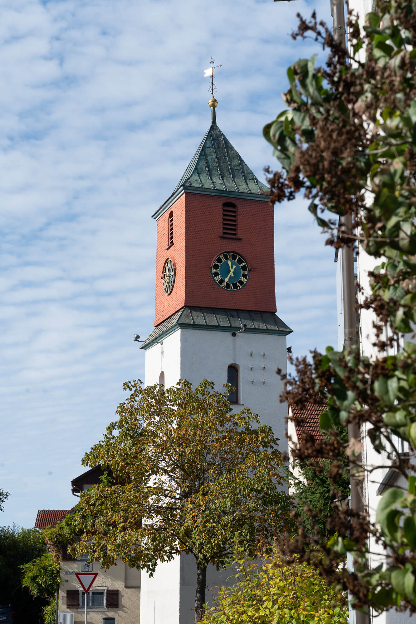 Turm in Trossingen mit Uhr und grünem Dach, eingerahmt von Bäumen