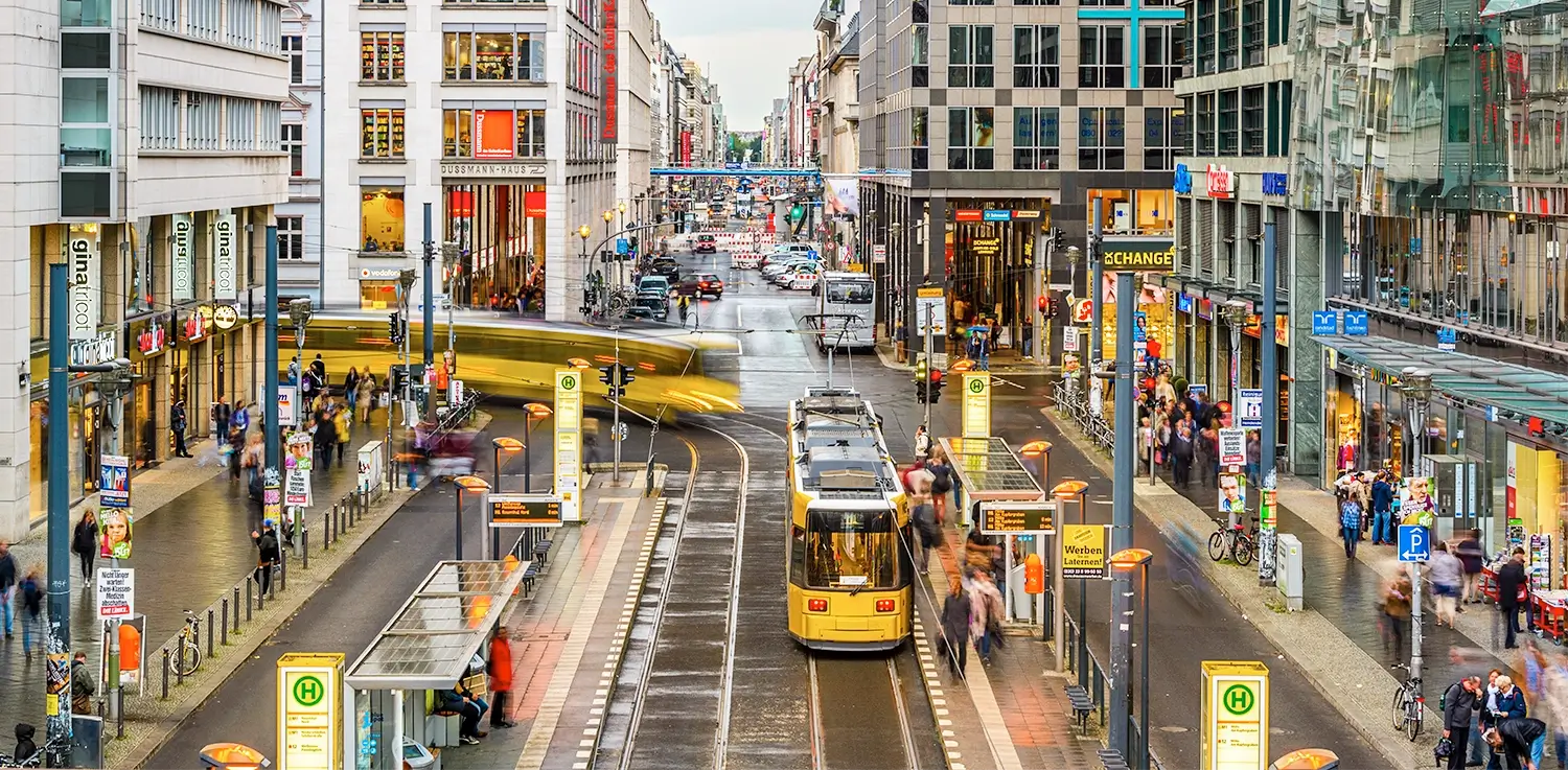 Busy street scene on Friedrichstrasse in Berlin with trams, shops, pedestrians, and modern city buildings