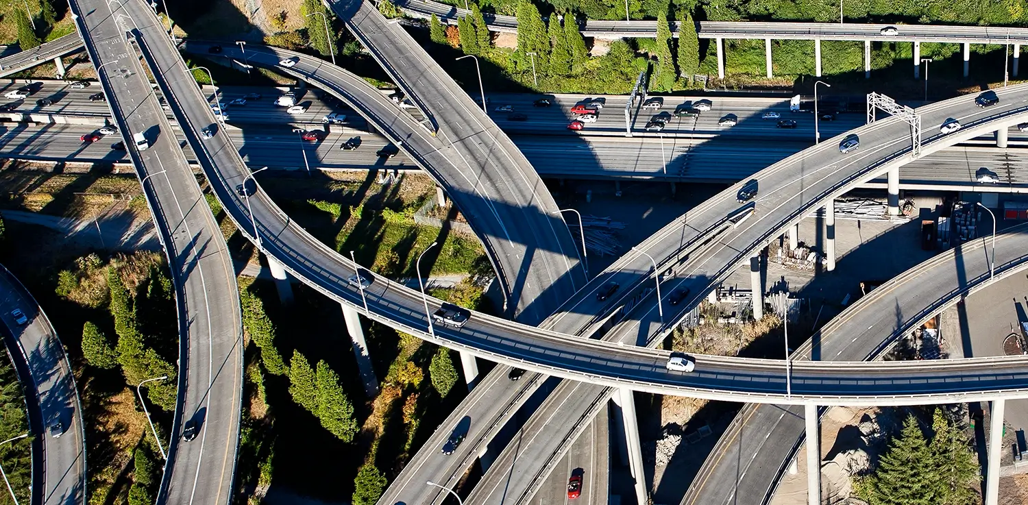 Aerial view of a multi-level highway interchange with curved overpasses, traffic, and surrounding greenery