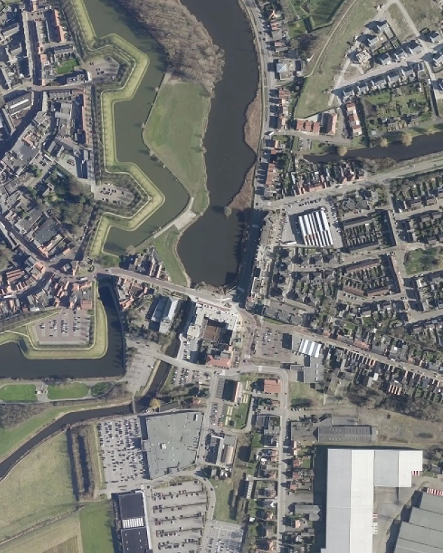 Top-down aerial view of a historic city with canals, roads, residential neighborhoods, and surrounding green spaces