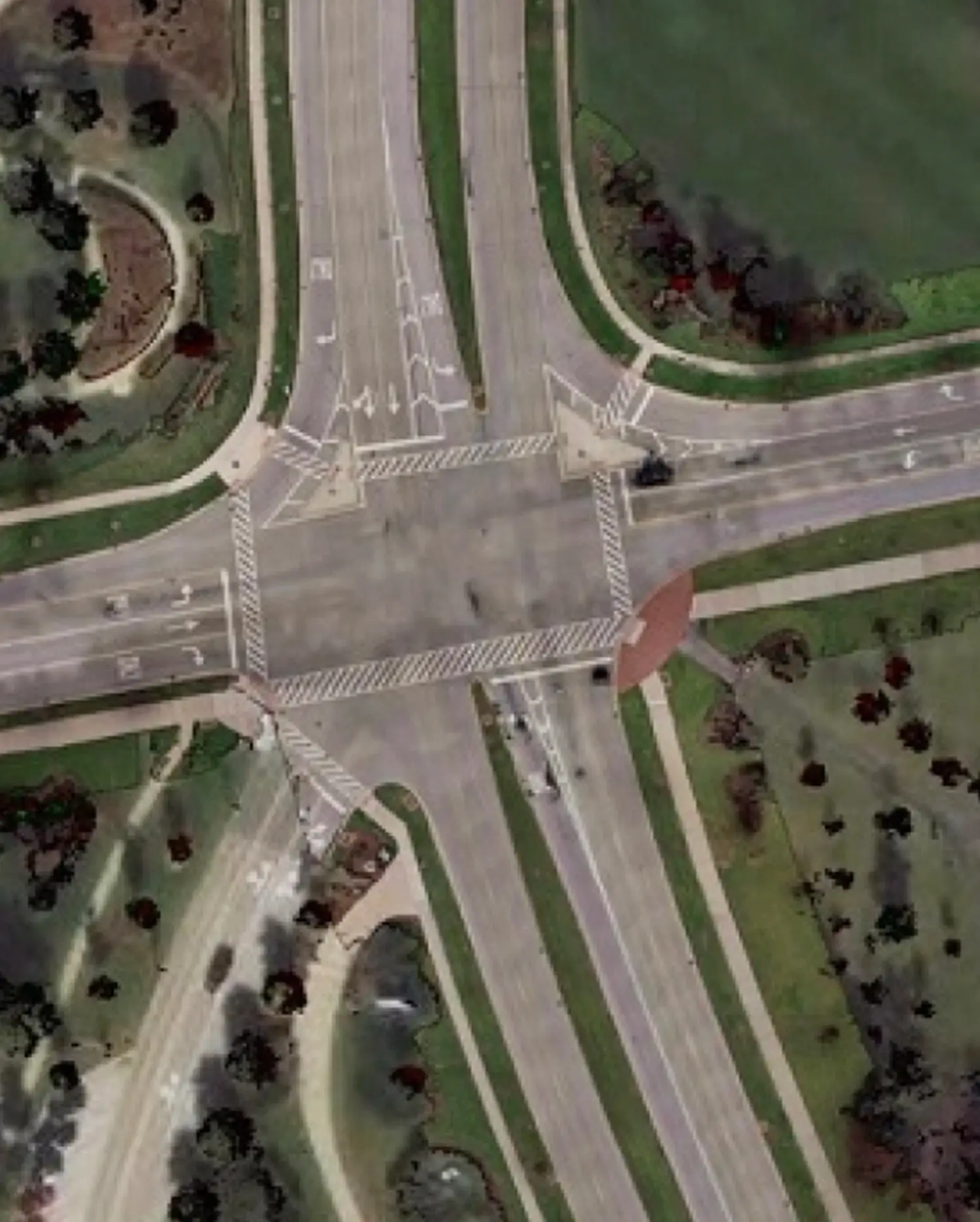 Street Ortho aerial view of a multi-lane road intersection with lane markings, sidewalks, and surrounding green space