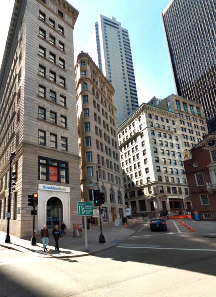 Downtown Boston street intersection with historic and modern high-rise buildings, pedestrians, and traffic in bright daylight