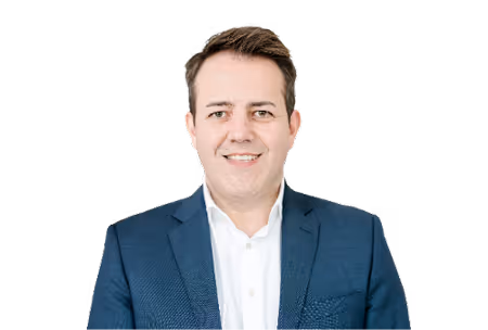 Smiling man wearing a white shirt and dark blue suit jacket on a white background.