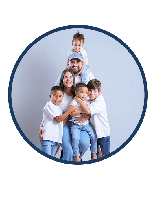 Smiling family of six posing together against a light gray backdrop.