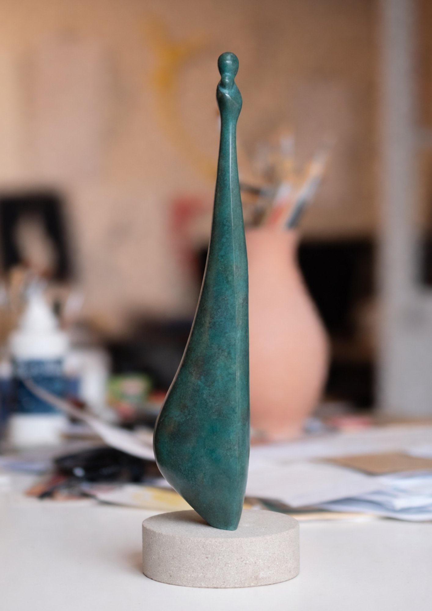 Sculpture Vierge à l'Enfant de l'Atelier Philippe Gancel en bronze sur socle rond en pierre, représentant une figure abstraite élancée.