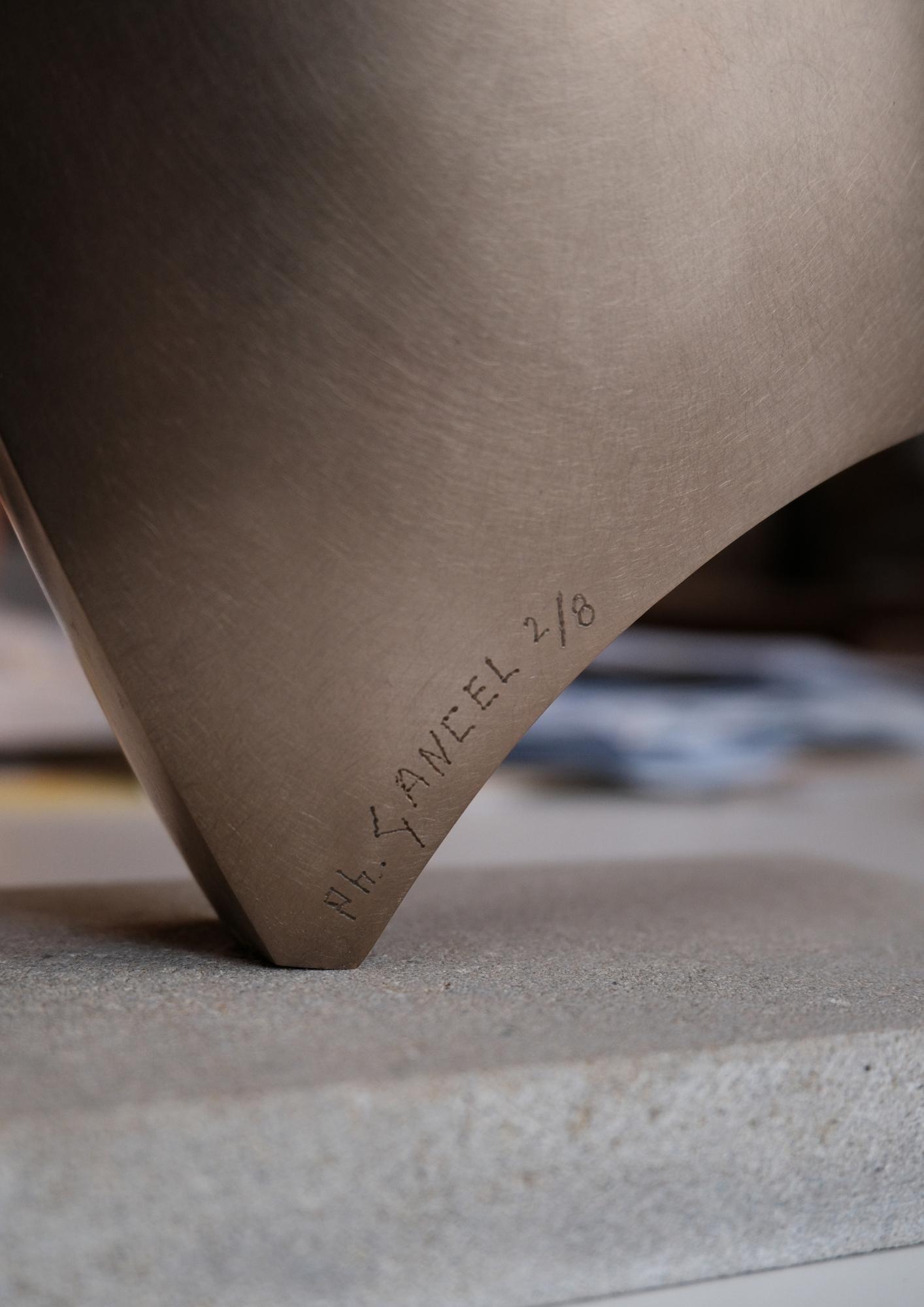 Gros plan sur le coin de la sculpture Confidence en bronze poli de l'Atelier Philippe avec une signature gravée "Ph. GANCEL 2/8" sur un socle en pierre.