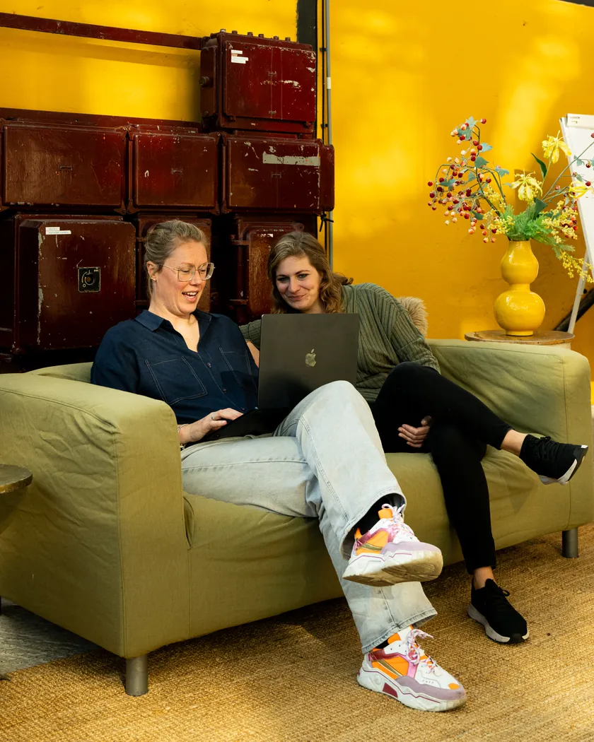 Rosanne en Esther van Buro Staal kijken samen op een laptop op de bank