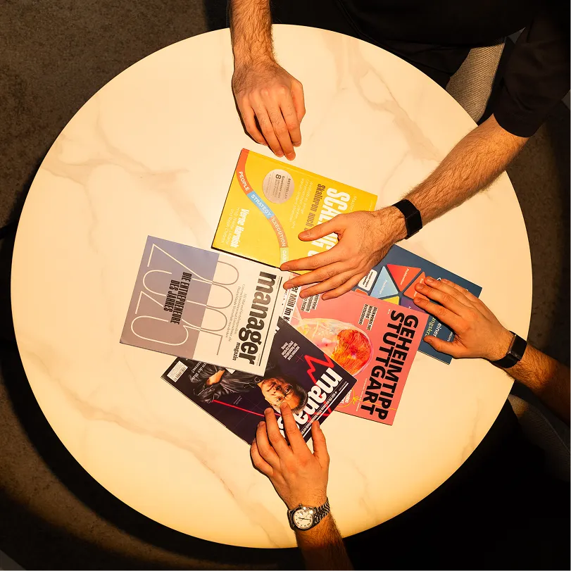 Hände mit Wirtschaftsmagazinen auf einem Tisch