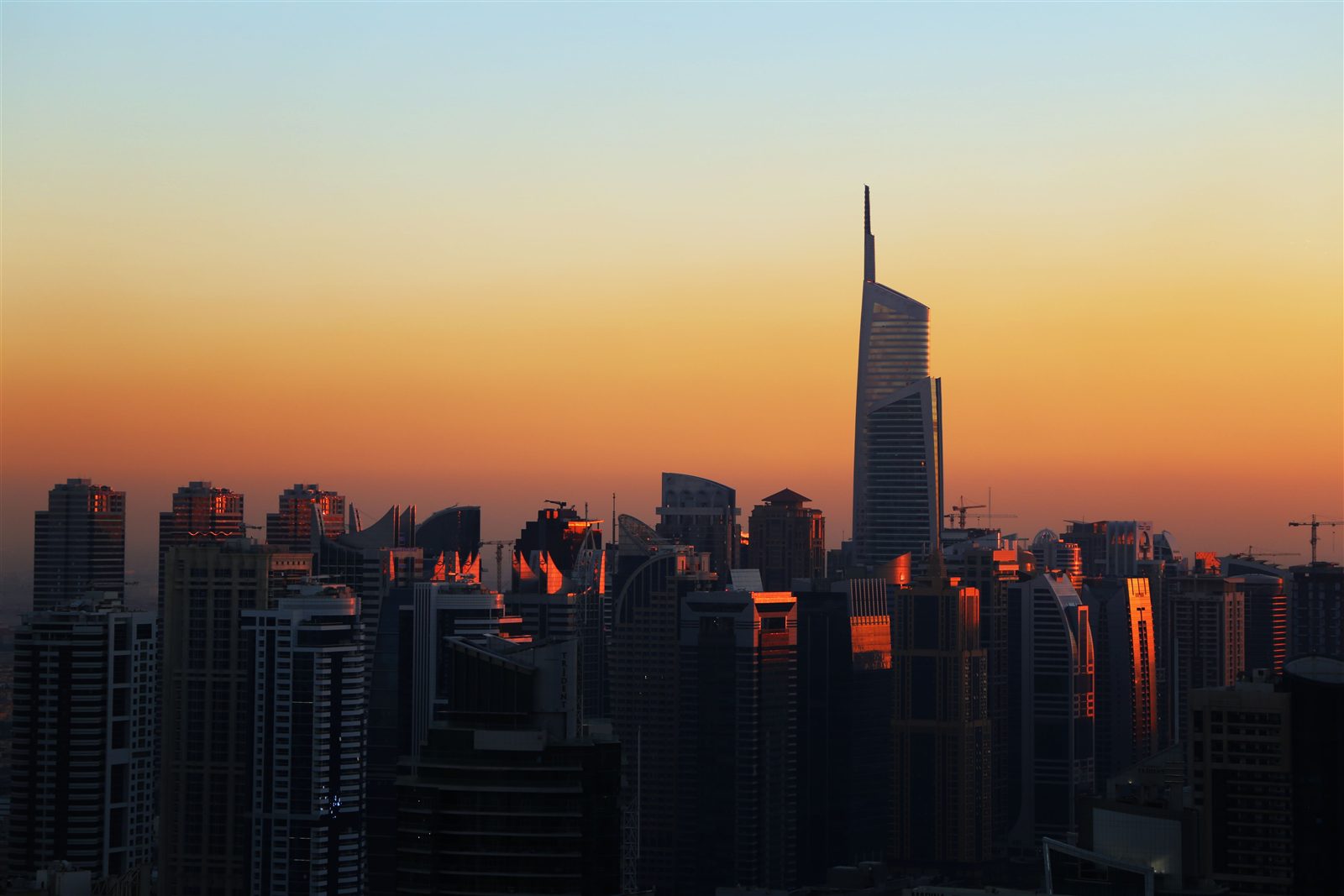 High-rise residential towers silhouetted against an orange sunset sky