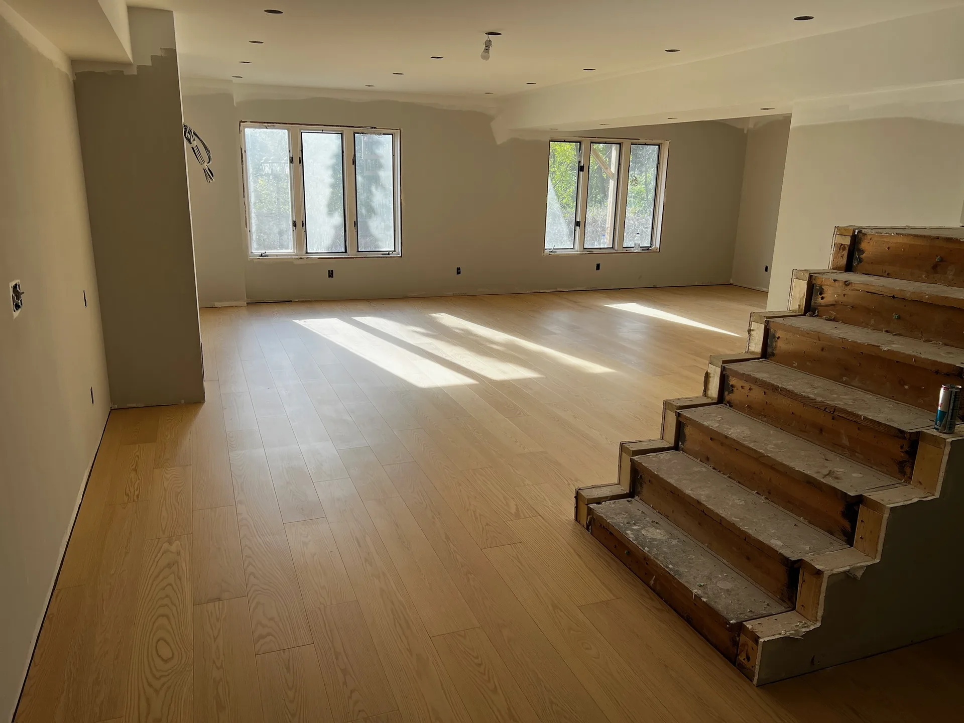 Light oak plank hardwood flooring with unfinished stairs