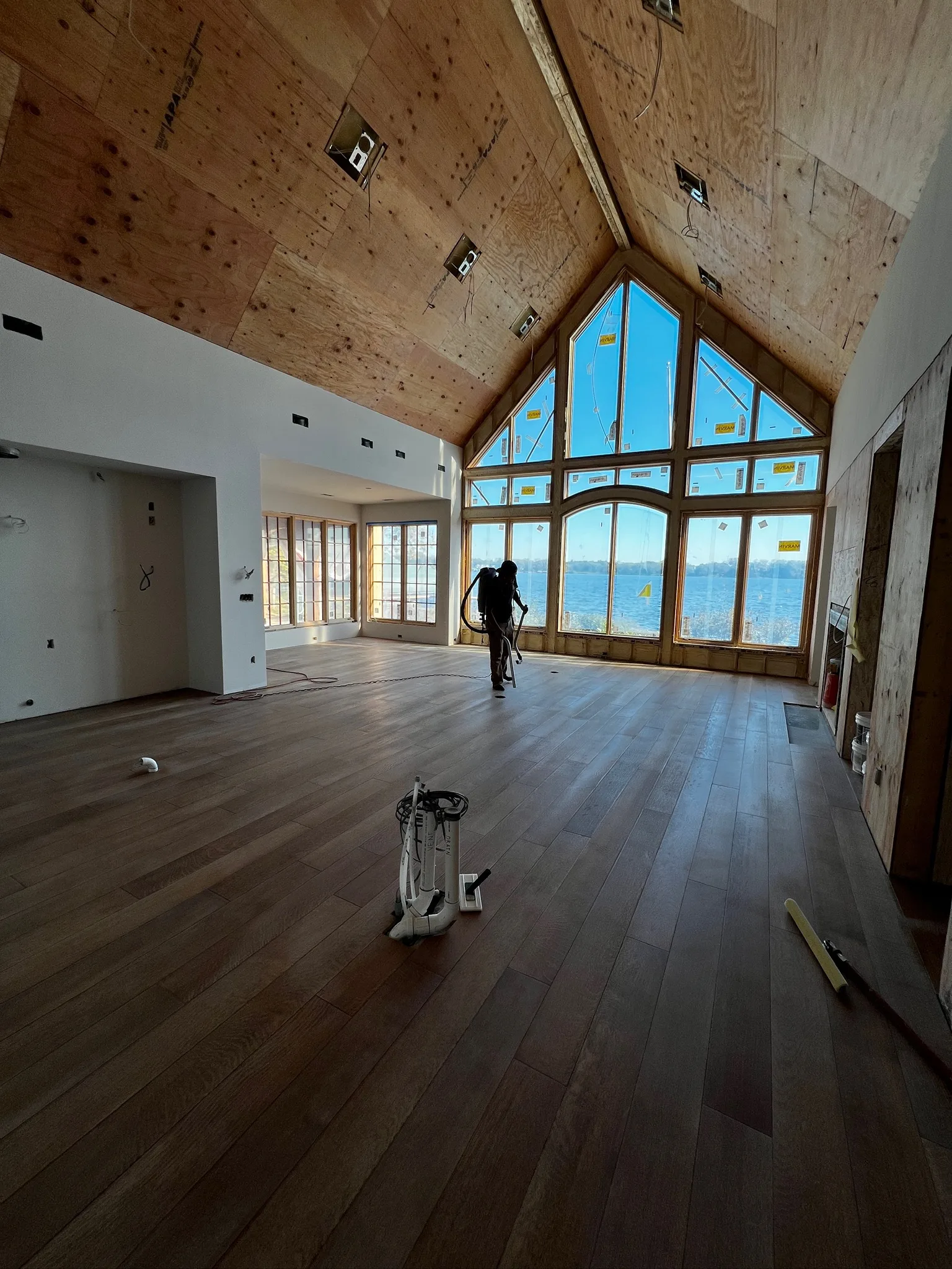 Worker sanding hardwood floors in A-frame lakefront home