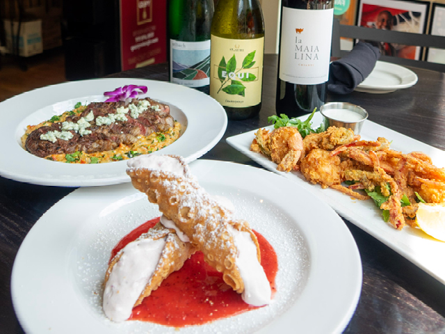 three plates of food on a table next to three bottles of wine
