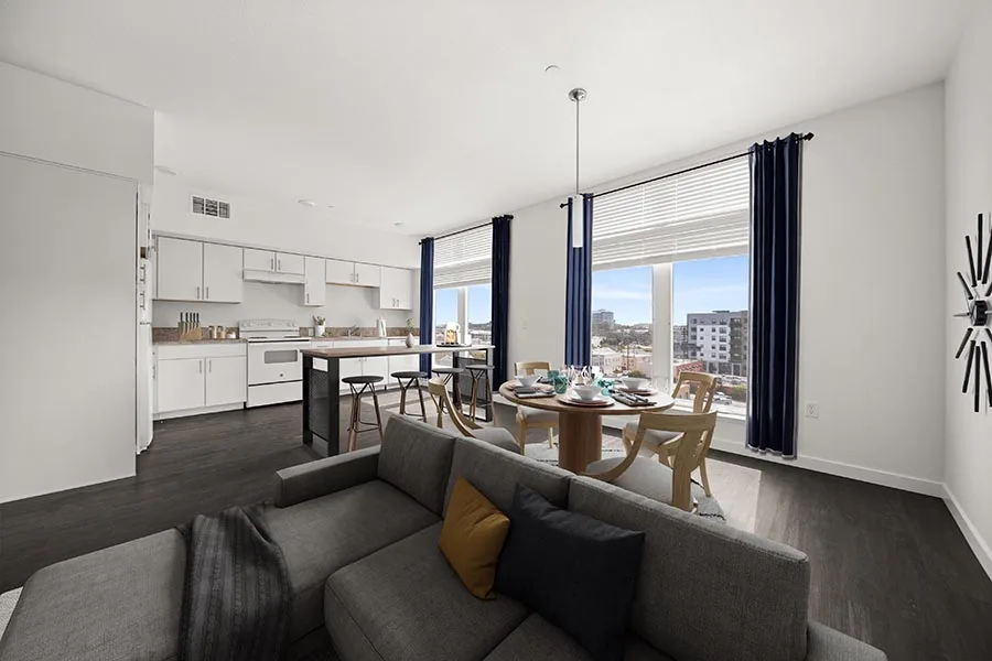 Virtually staged living and dining area featuring sofa, table, chairs and kitchen with white cabinets