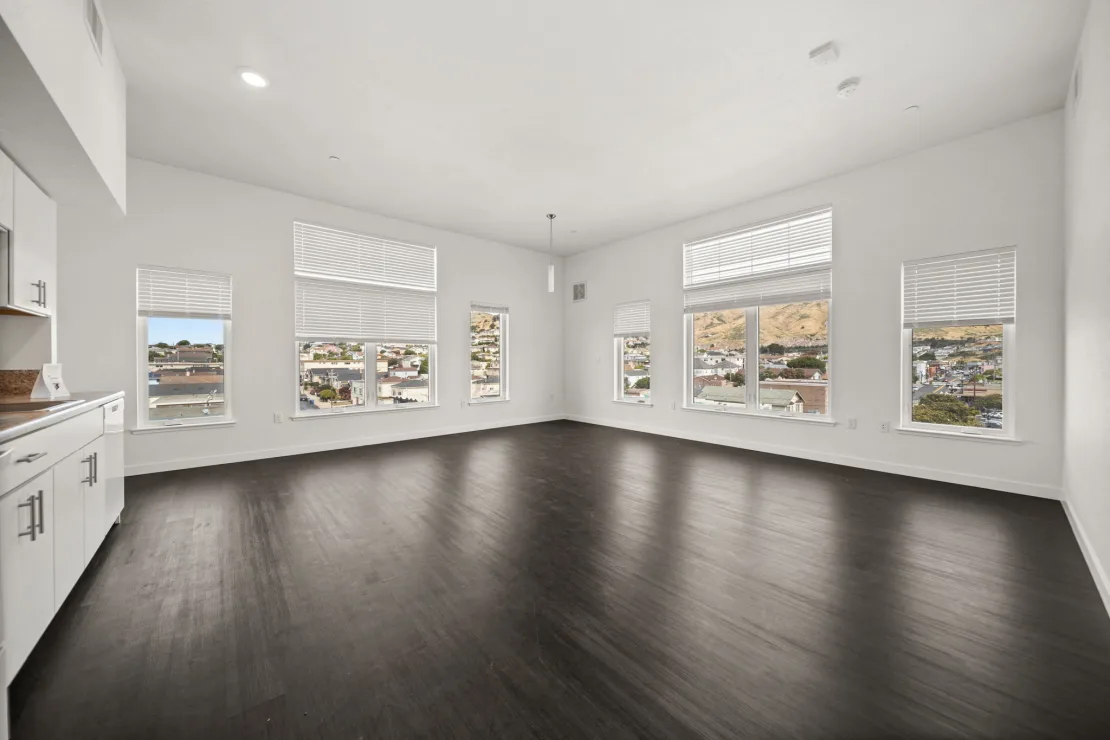 Unfurnished apartment unit with kitchen with white cabinets and large windows