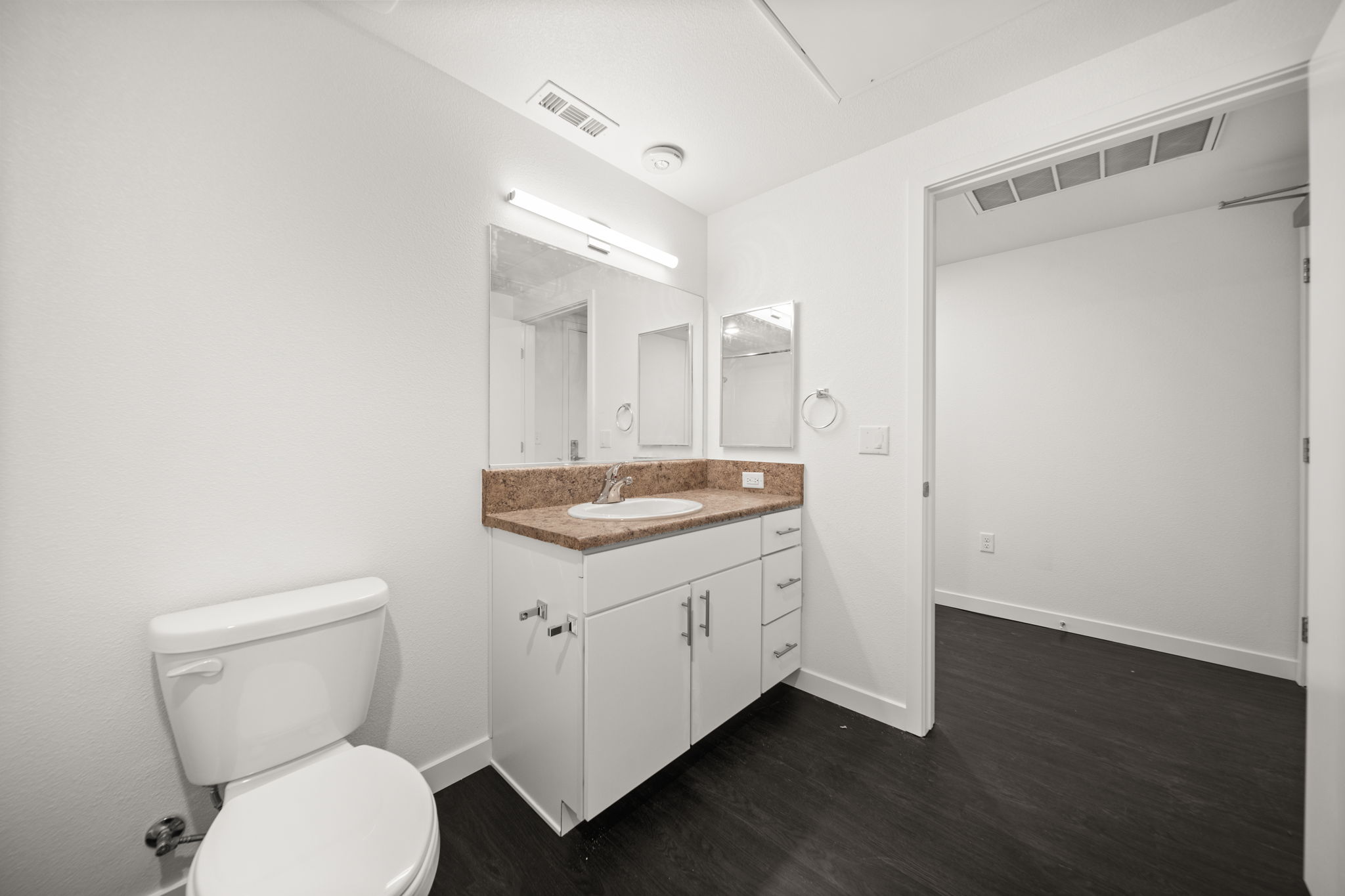 Bathroom with white cabinets and view into hallway