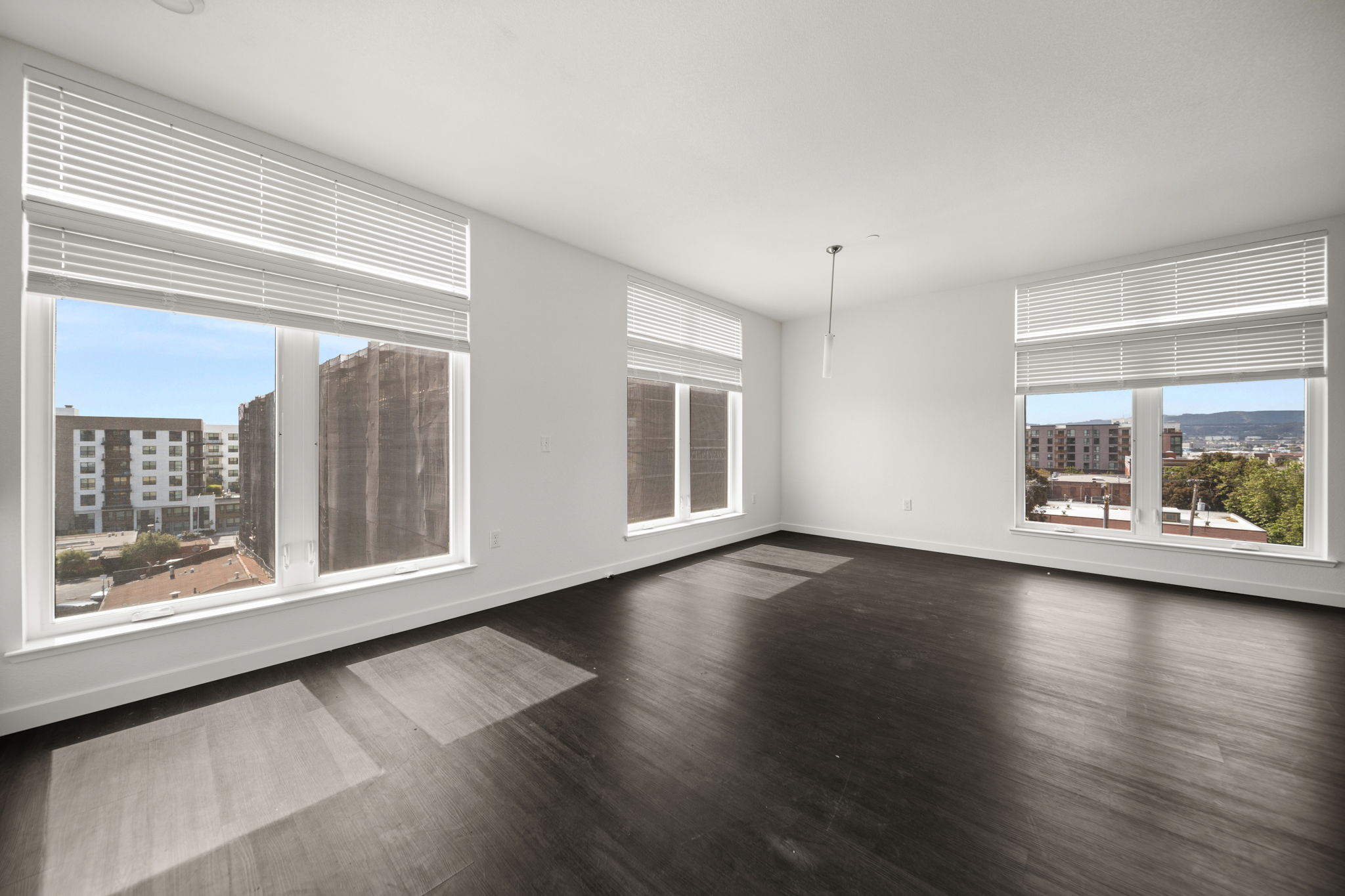 Unfurnished living area with wood floors and large windows