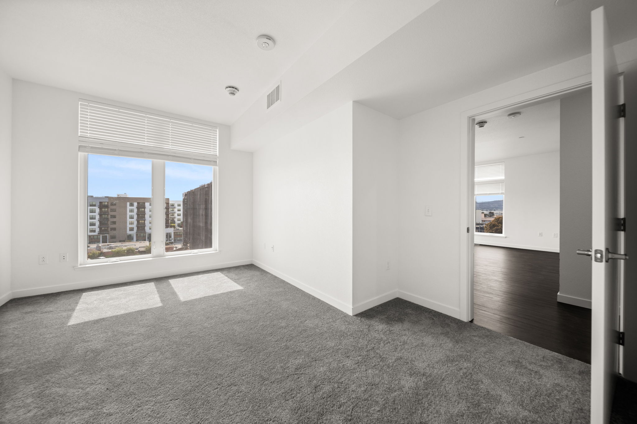 Unfurnished Bedroom with large window and view into living area