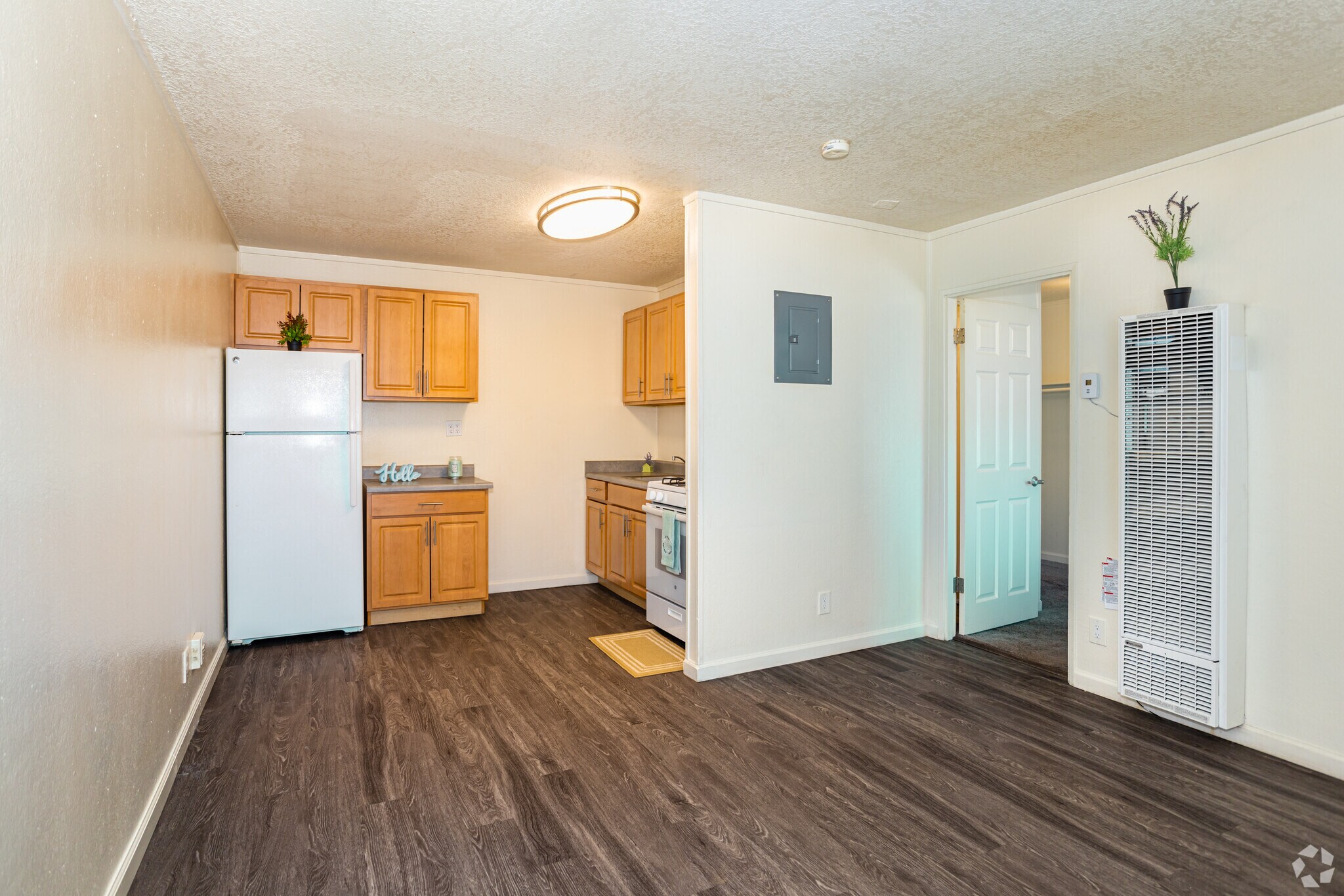 View from living room into kitchen with brown cabinets and white appliances