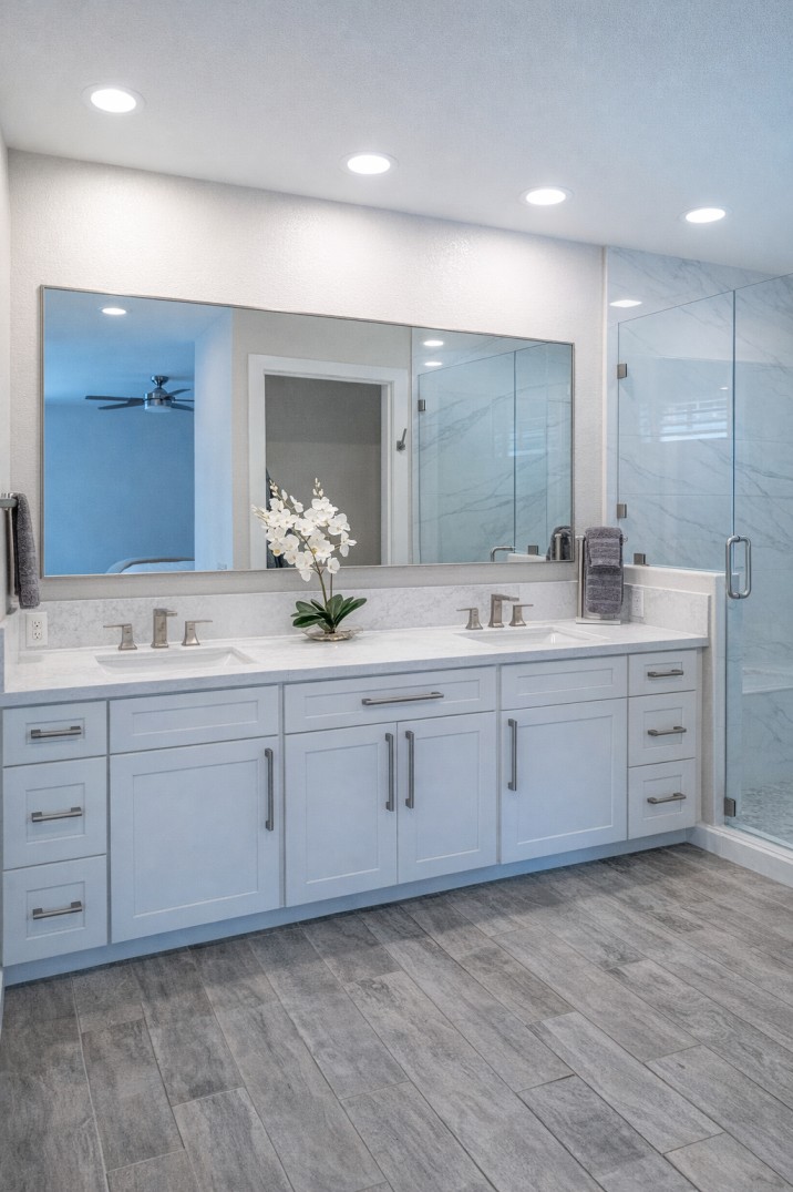 Modern bathroom shower with glass doors, marble walls, mosaic tile floor, and black rain showerhead and fixtures.