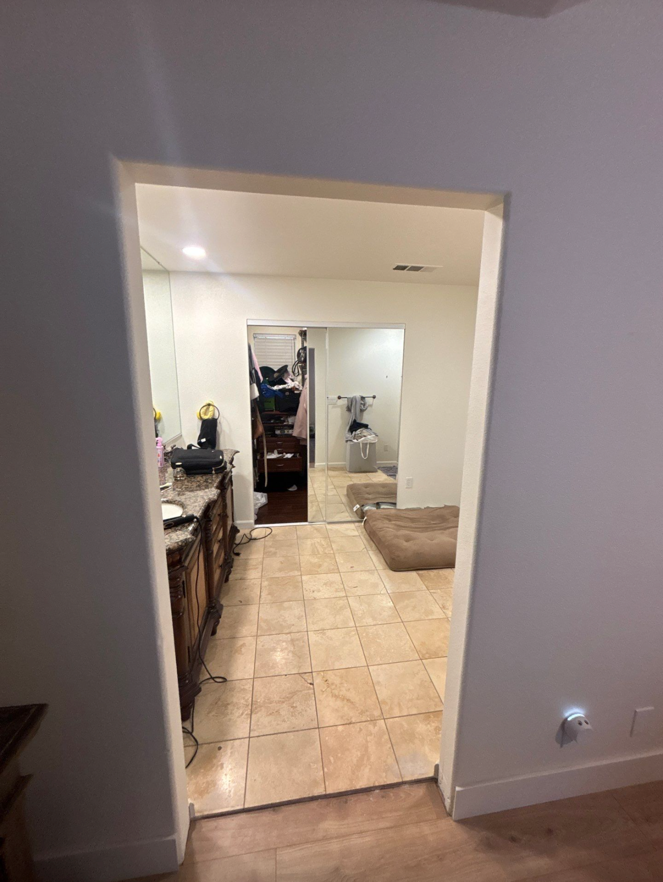 Modern Sacramento bathroom with a large bathtub, double sink vanity with cluttered countertop, tile flooring, and glass shower enclosure.