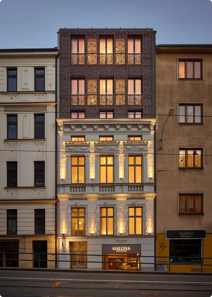 Fasáda moderního a historického domu s osvětlenými okny a kavárnou Gallina v přízemí.
