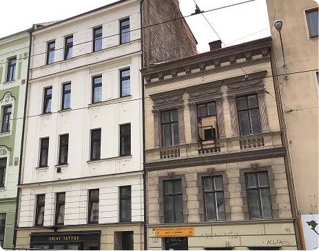 Two adjacent multi-story buildings with windows and a tattoo shop on the ground floor in an urban area.