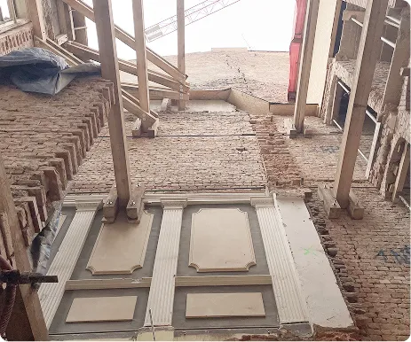 Pohled nahoru na zdi budovy s odhalenými cihlovými strukturami během rekonstrukce.