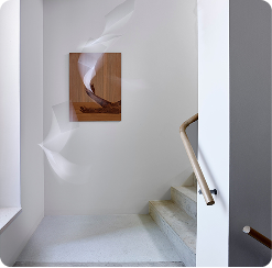 Modern white stairwell with a wooden handrail and abstract brown artwork on the wall.