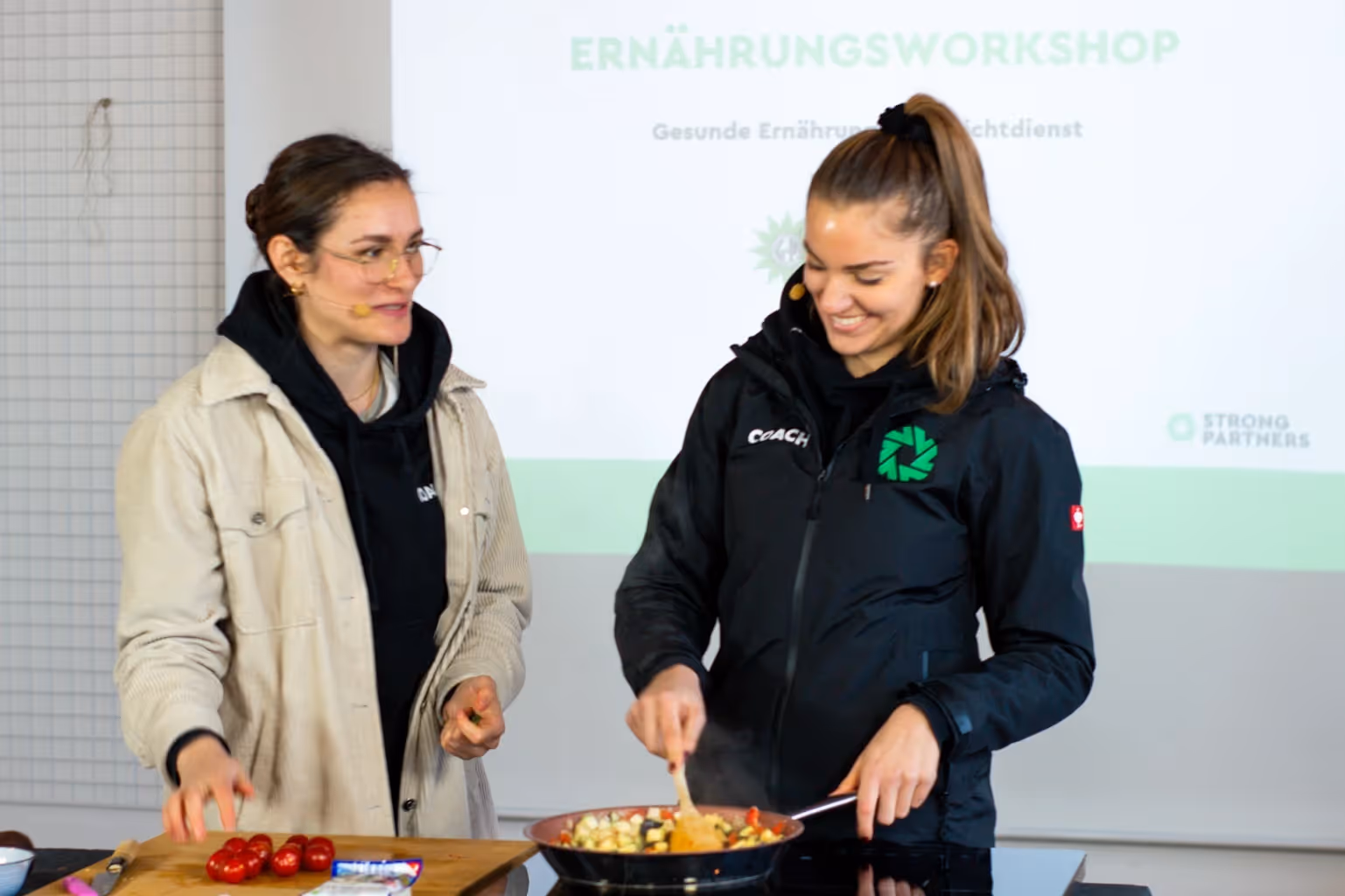 Zwei Coaches führen einen interaktiven Ernährungsworkshop mit Kochaktion durch
