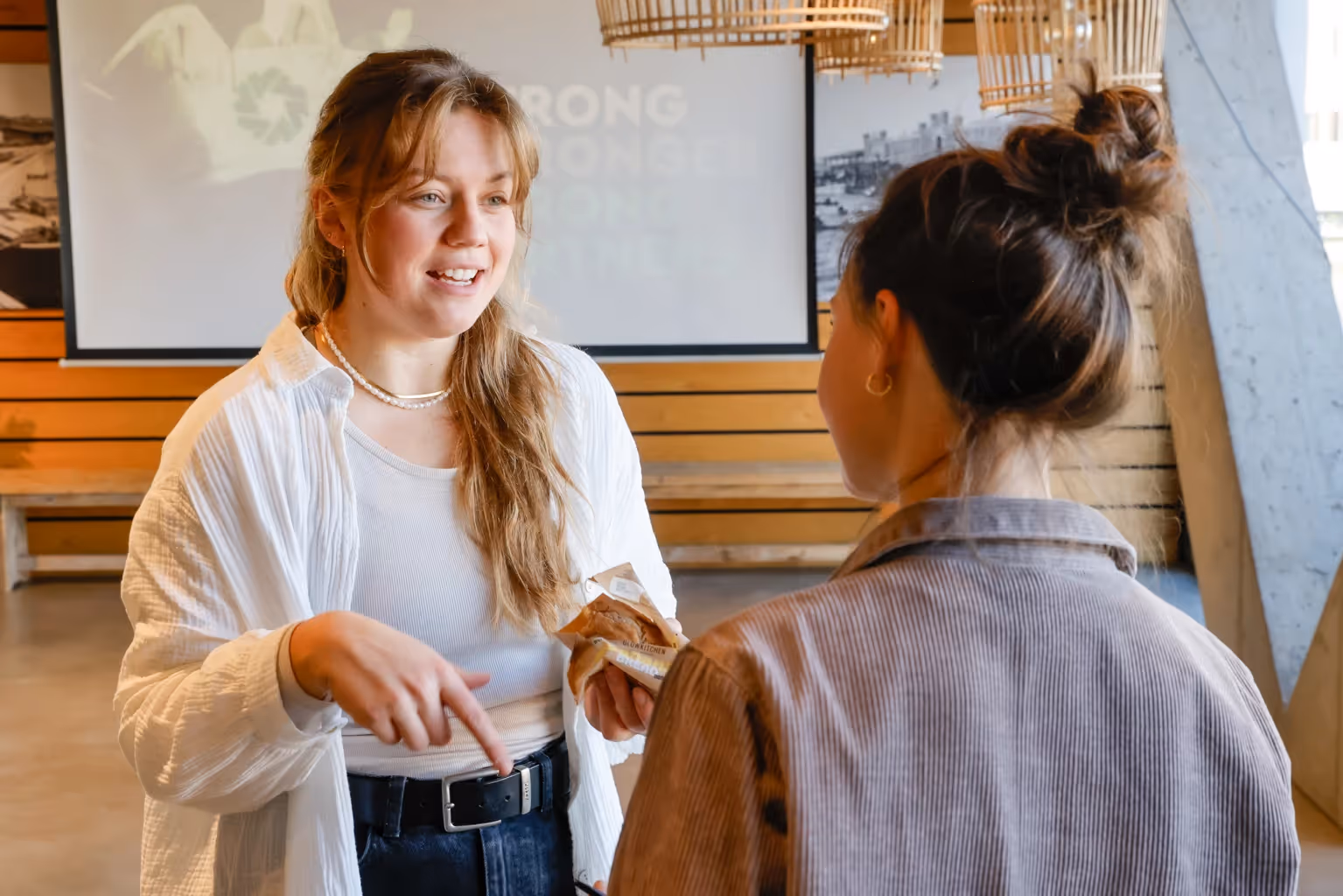 Zwei Frauen die sich unterhalten und im Hintergrund eine Präsentation
