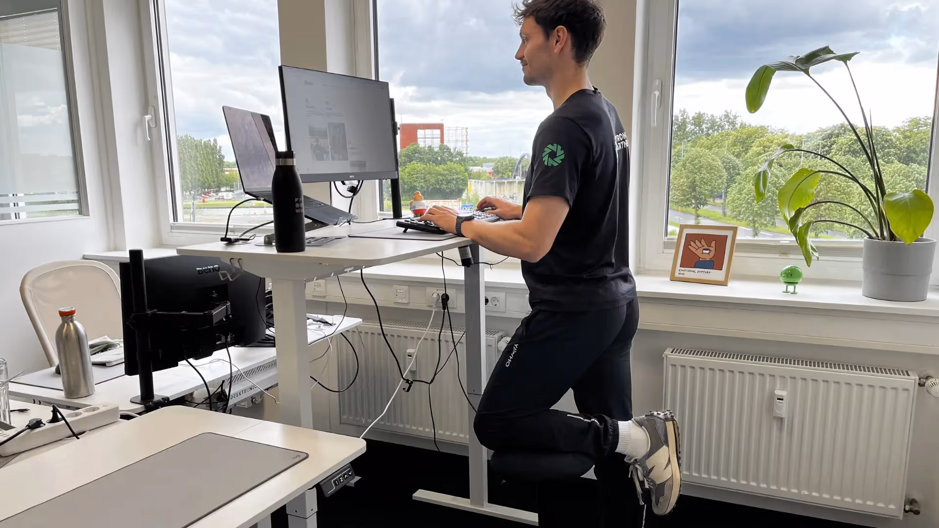 Mann steht an einem Stehschreibtisch mit einem ergonomischen Hilfsmittel