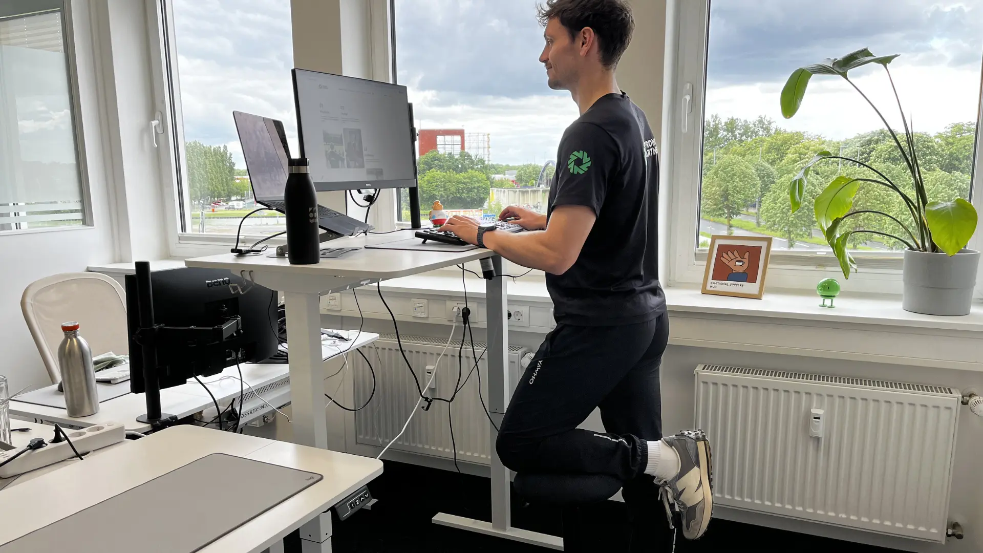 Mann steht an einem Stehschreibtisch mit einem ergonomischen Hilfsmittel