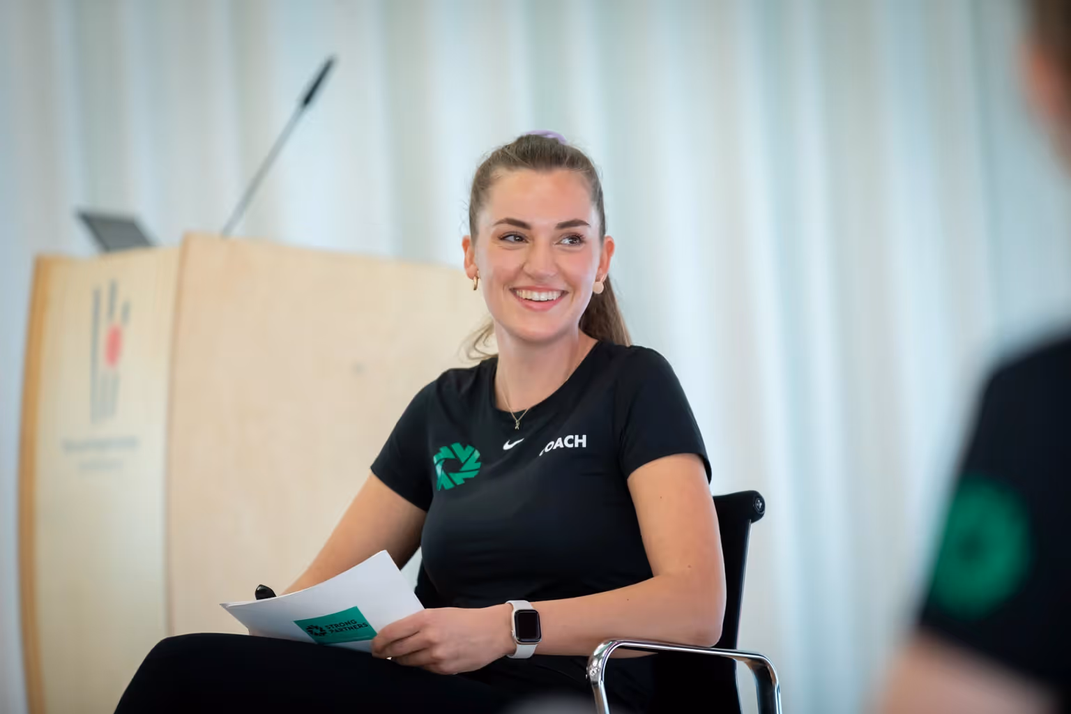 Paula Menninghaus sitzt mit Moderationskarten in der Hand auf einem Stuhl