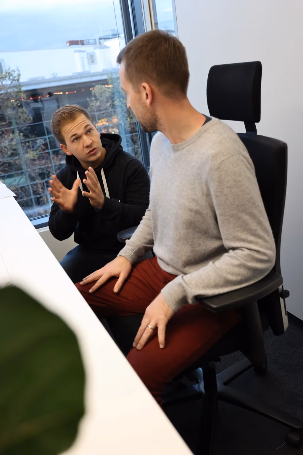 Ein Strong Partners Coach sitzt neben jemanden an einem ergonomischen Arbeitsplatz