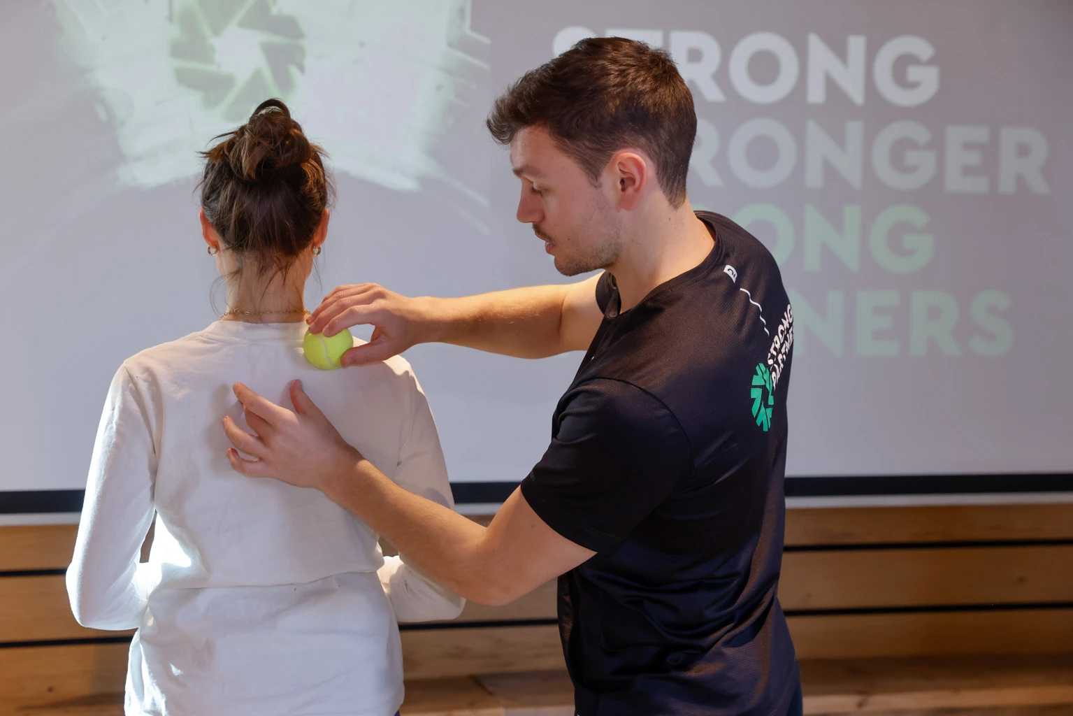 Strong Partners Coach bei einer Rückenübung mit dem Tennisball
