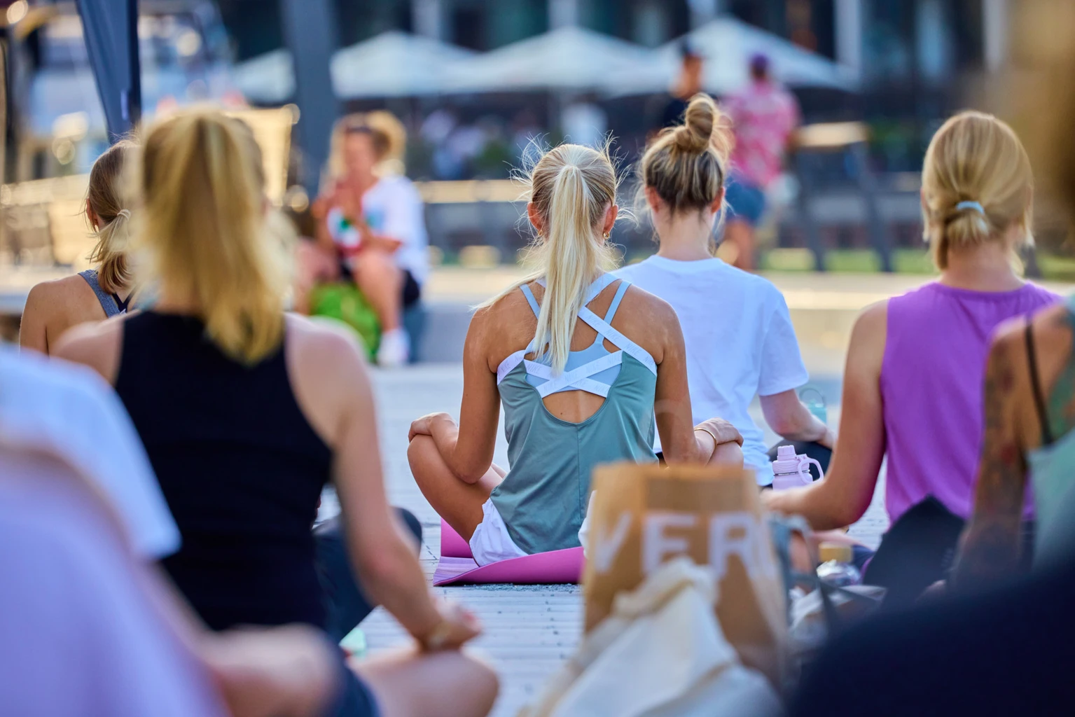 Yoga-Teilnehmerinnen von hinten im Schneidersitz