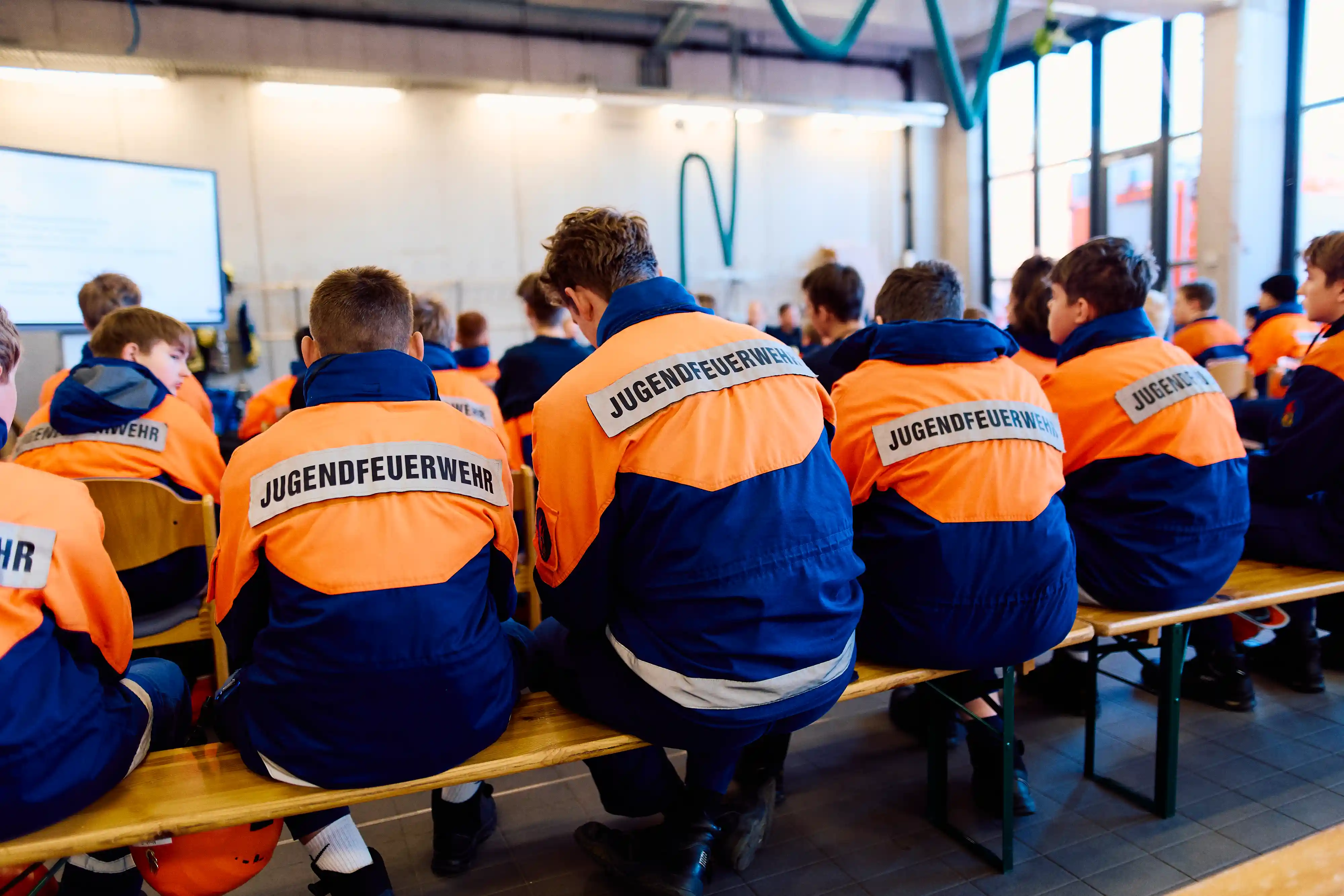 Jugendfeuerwehr an Bierbänken bei einem Event in Feuerwehr-Kleidung