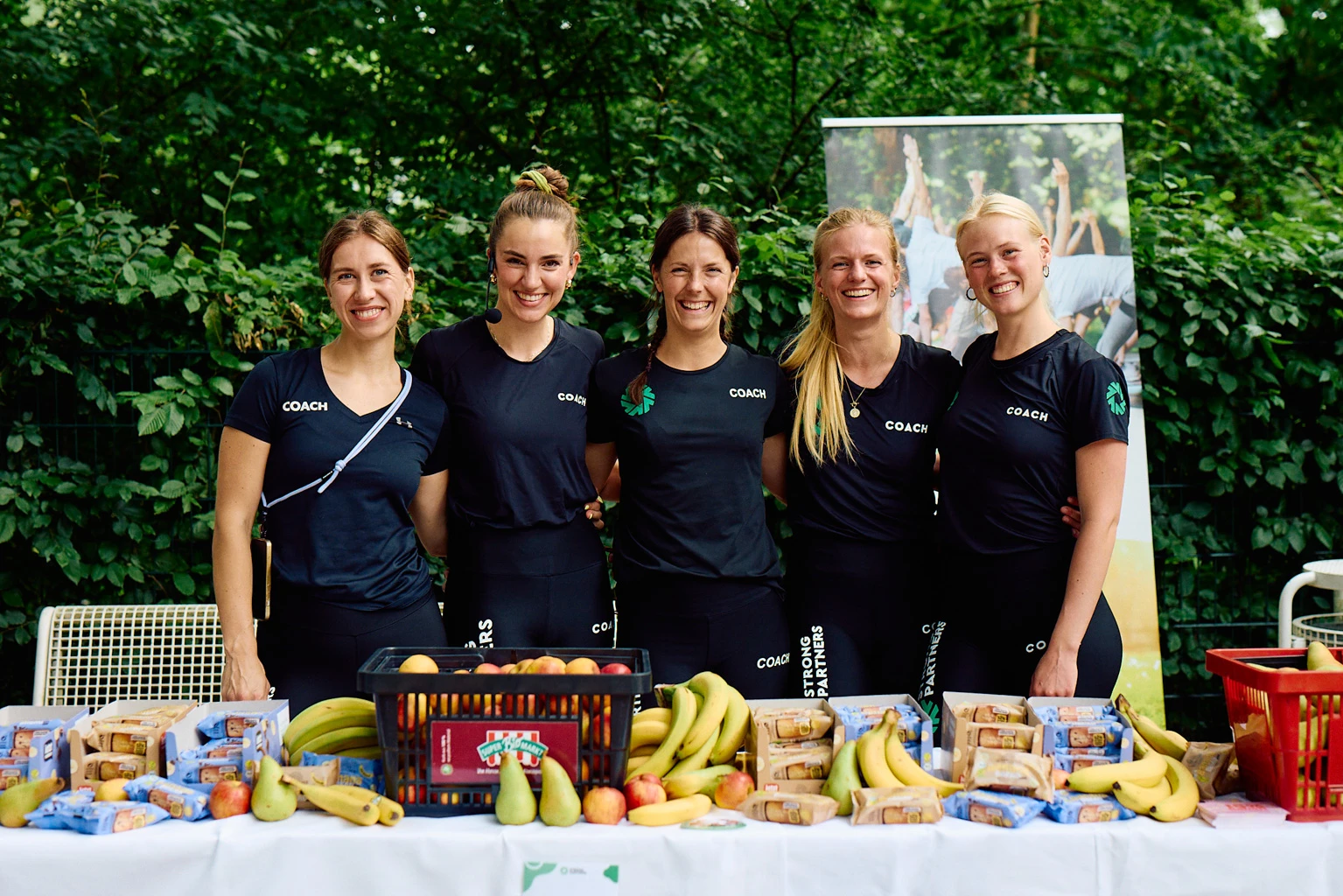 Strong Partners Coaches hinter einer Theke voll mit frischem Obst
