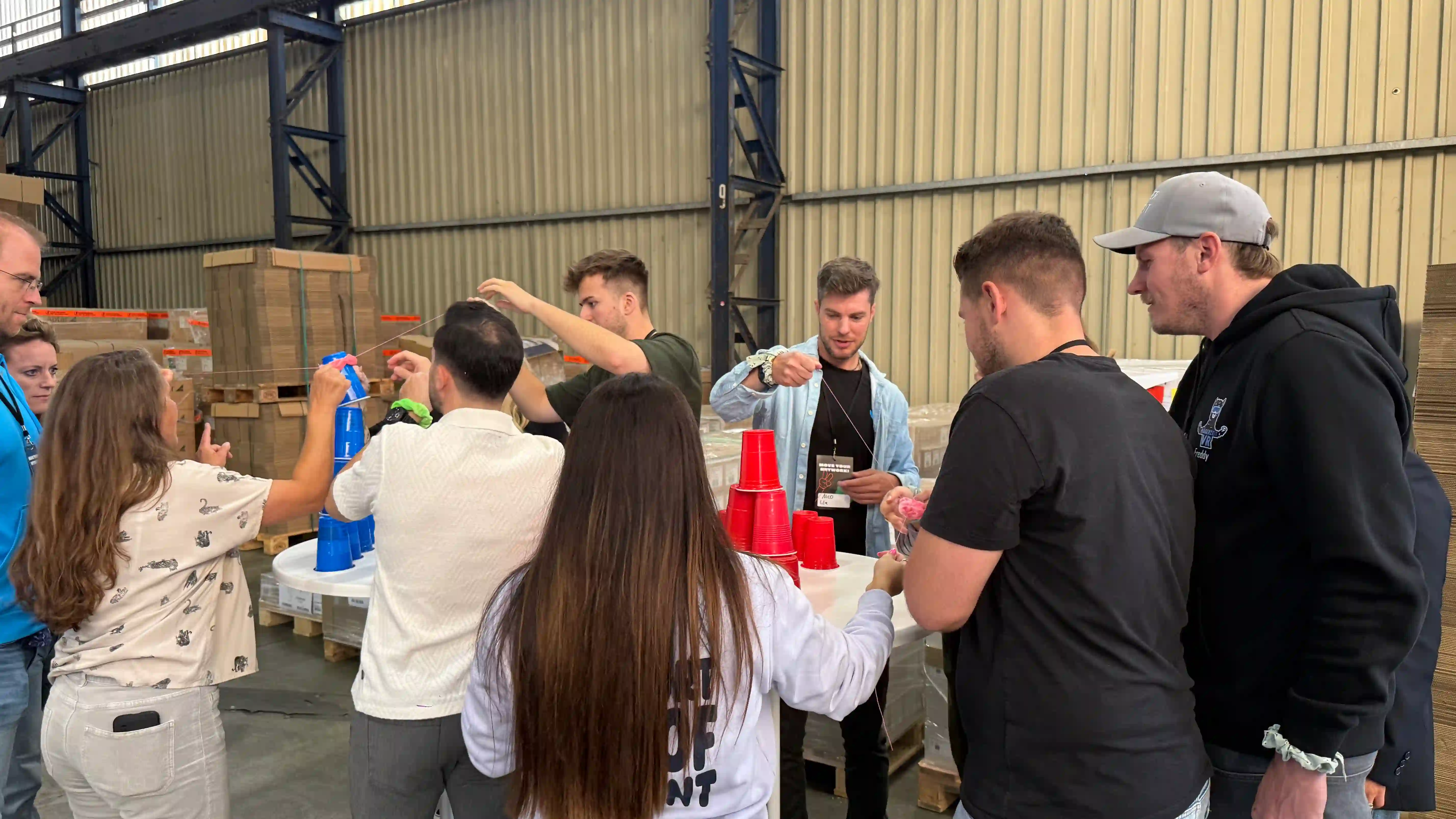Ein Team spielt das Spiel Becher-Pyramide, bei dem Konzentration und ruhiges Händchen gefragt sind