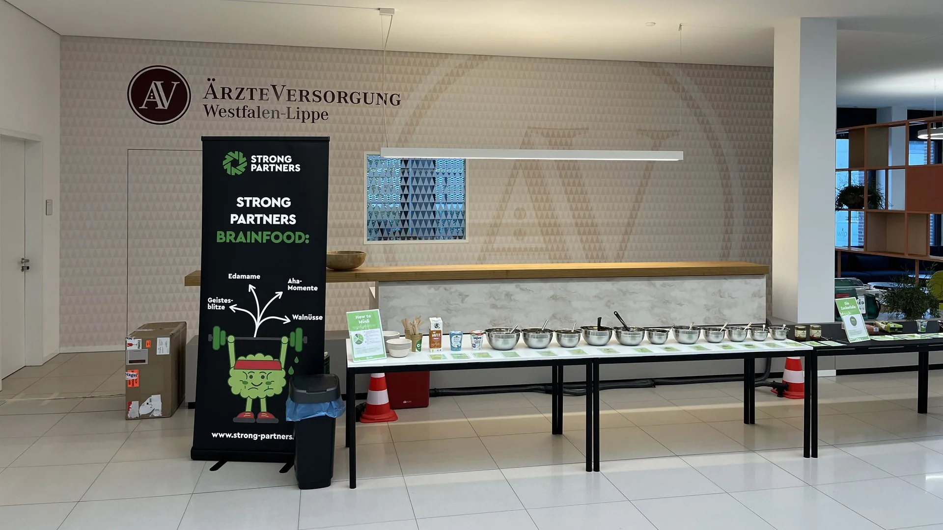 Aufgebautes How-to-Müsli-Buffet mit Stationen und Brainfood-Roll-up von Strong Partners im Foyer eines Unternehmens