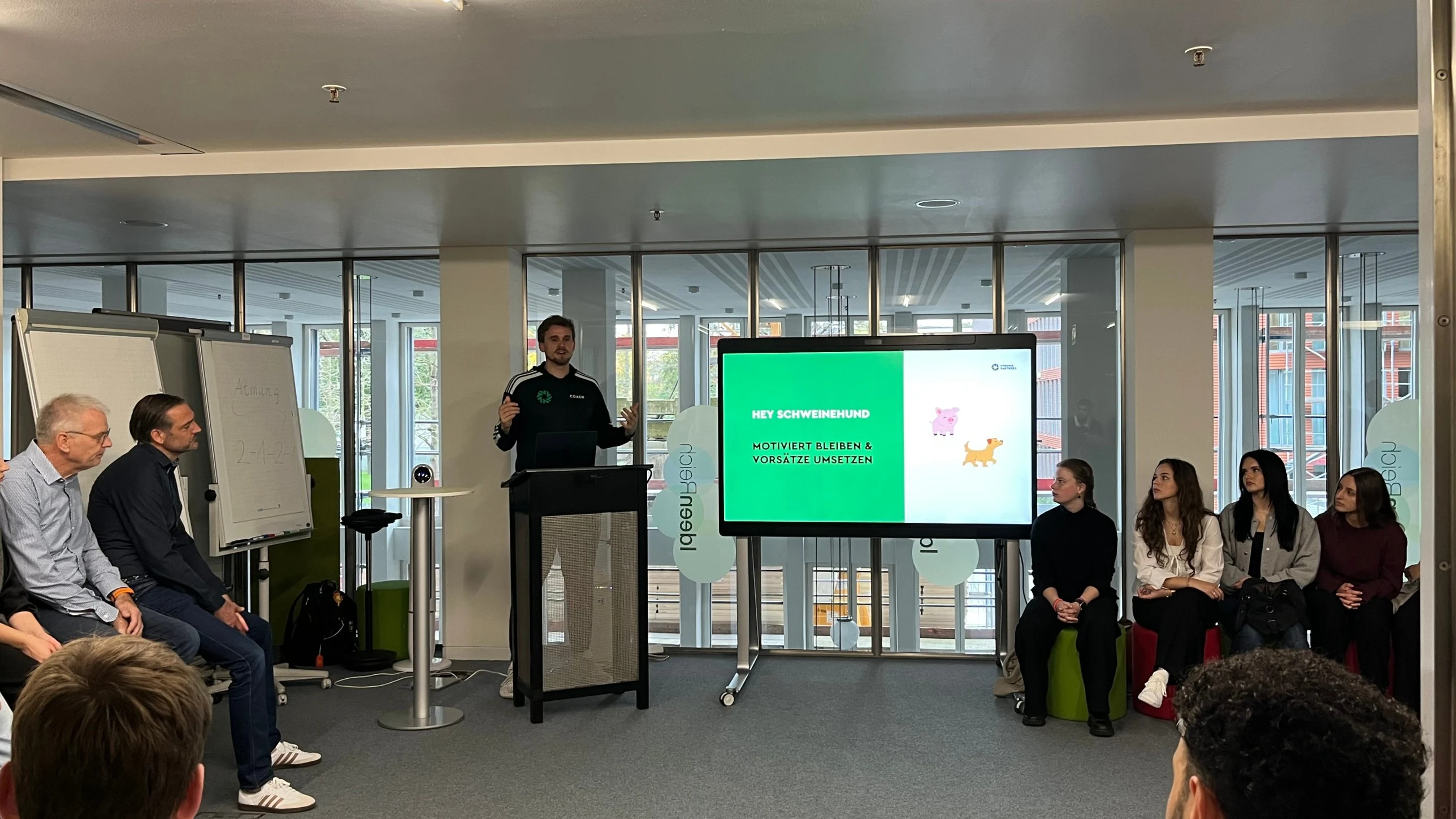 Strong Partners Coach hält beim Azubi-Gesundheitstag einer Sparkasse einen Vortrag „Hey Schweinehund” vor sitzenden Auszubildenden.