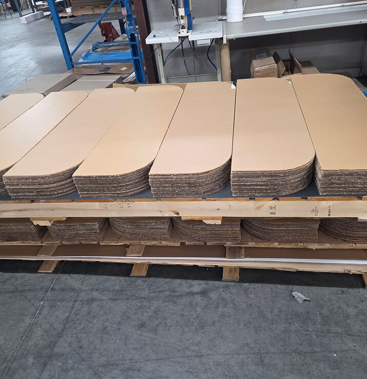 Stacks of die-cut kraft cardboard blanks on a warehouse pallet