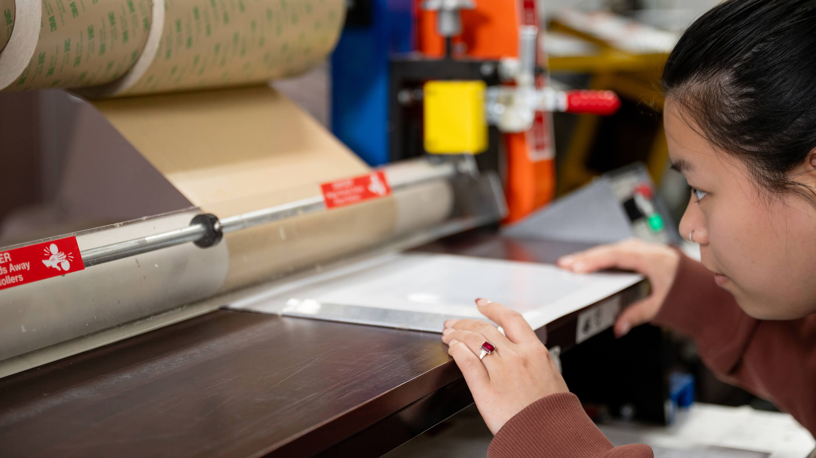 Close-up of a worker aligning a sheet at a laminator feed table