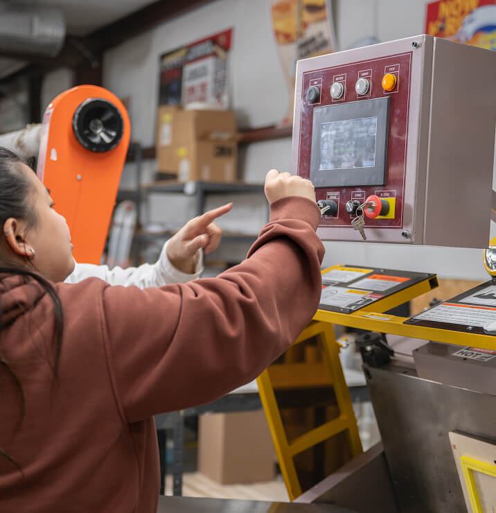A worker operating the control panel of a die-cutting machine