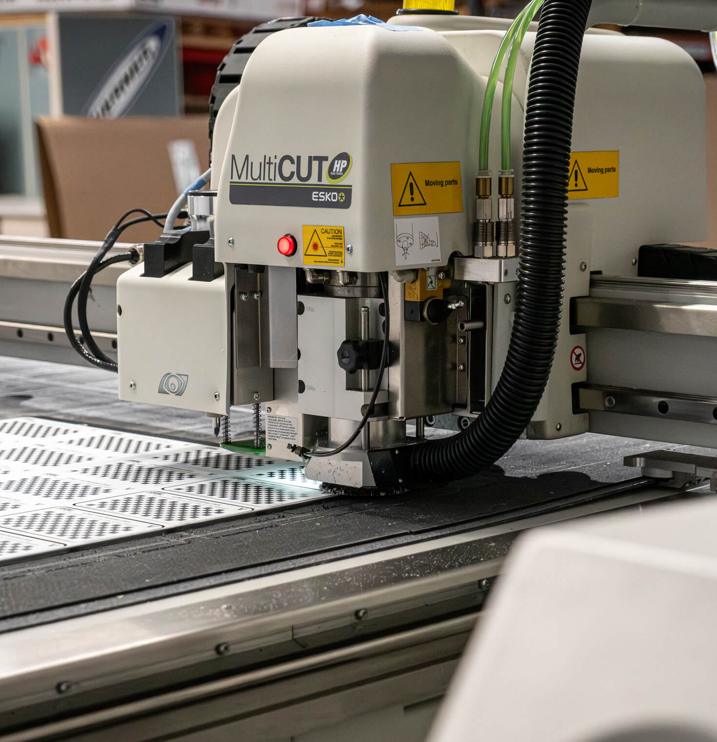 An Esko MultiCUT flatbed router cutting a printed sheet of labels